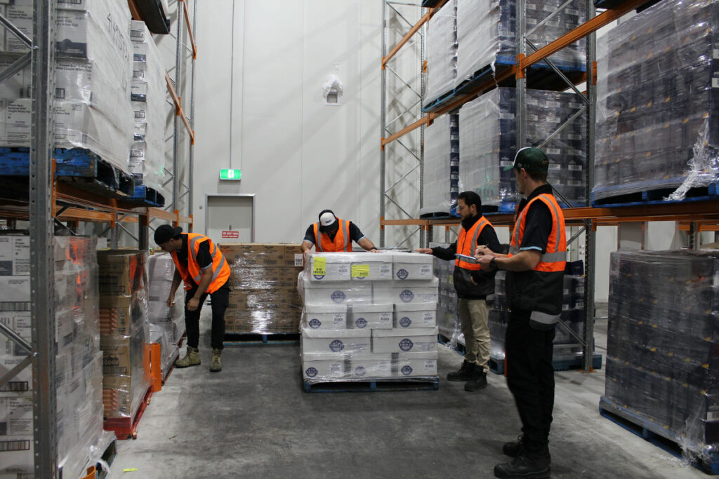 Staff organizing frozen goods in temperature-controlled cold freight area