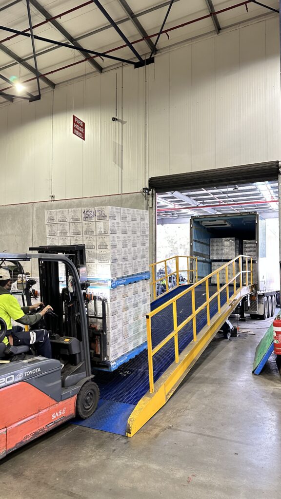 Forklift loading palletized goods into refrigerated transport truck